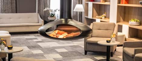 A modern living room with a fireplace, sofas, and a bookshelf.