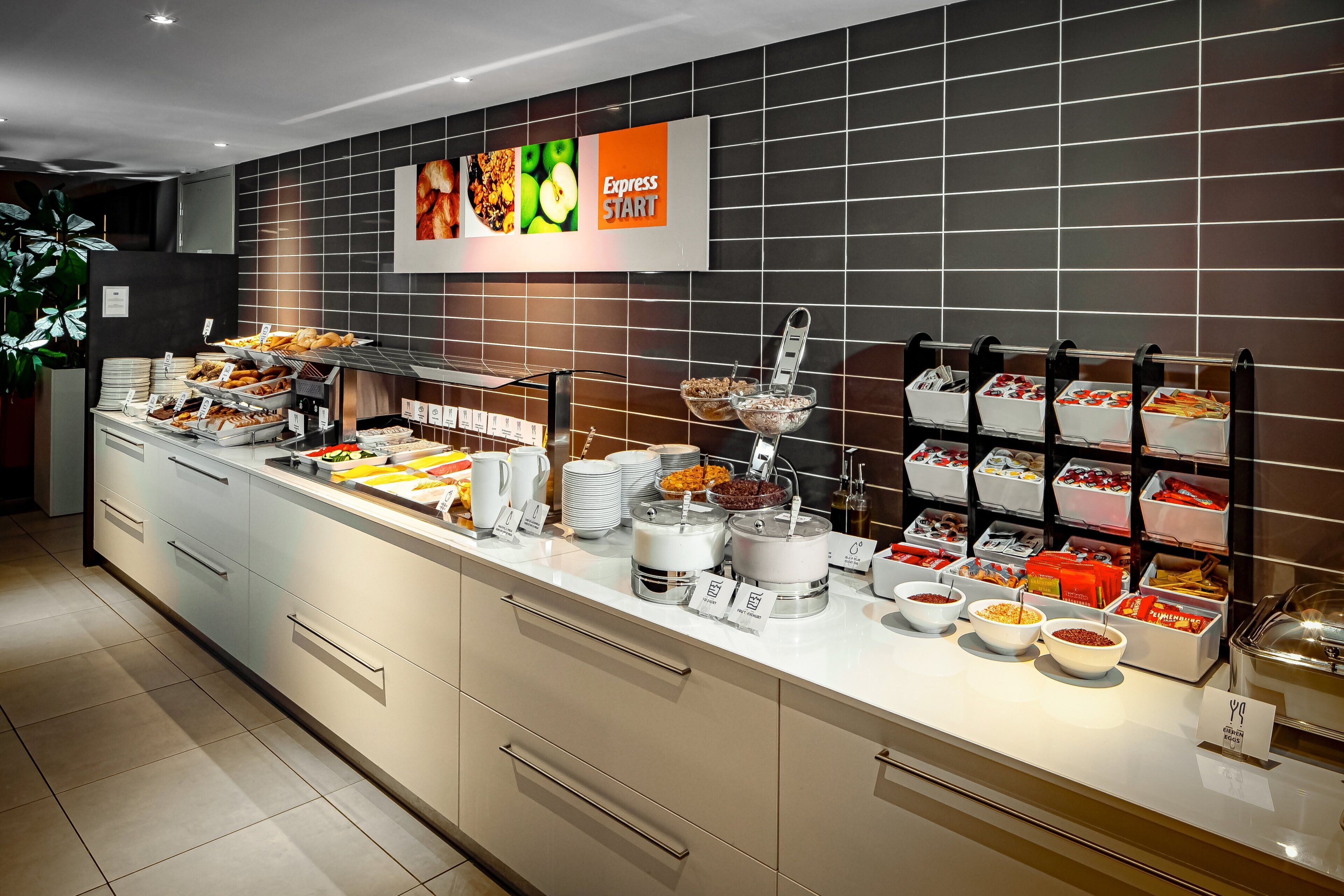 A buffet area with various food stations, including a section labeled 'Express Start' with a selection of fruits and pastries.