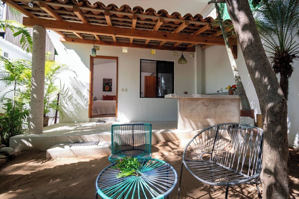 Un patio con dos sillas de metal, una pequeña mesa redonda y una zona de bar con barra de hormigón.