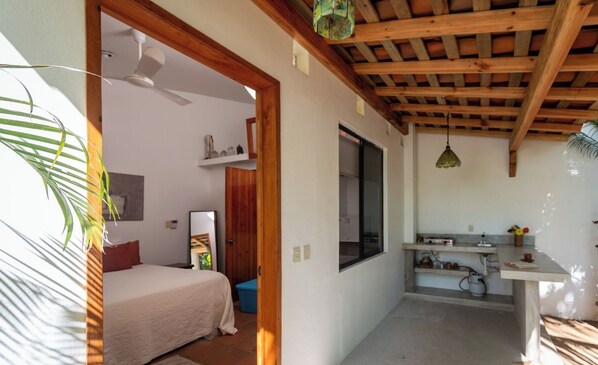 Une chambre à coucher de taille réduite, comprenant un lit, un plafond en bois, une petite salle de bain et un coin cuisine.
