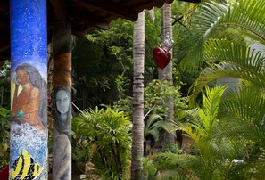 Un jardin tropical orné d’une fresque sur une colonne, avec des palmiers et un décor suspendu en forme de cœur.