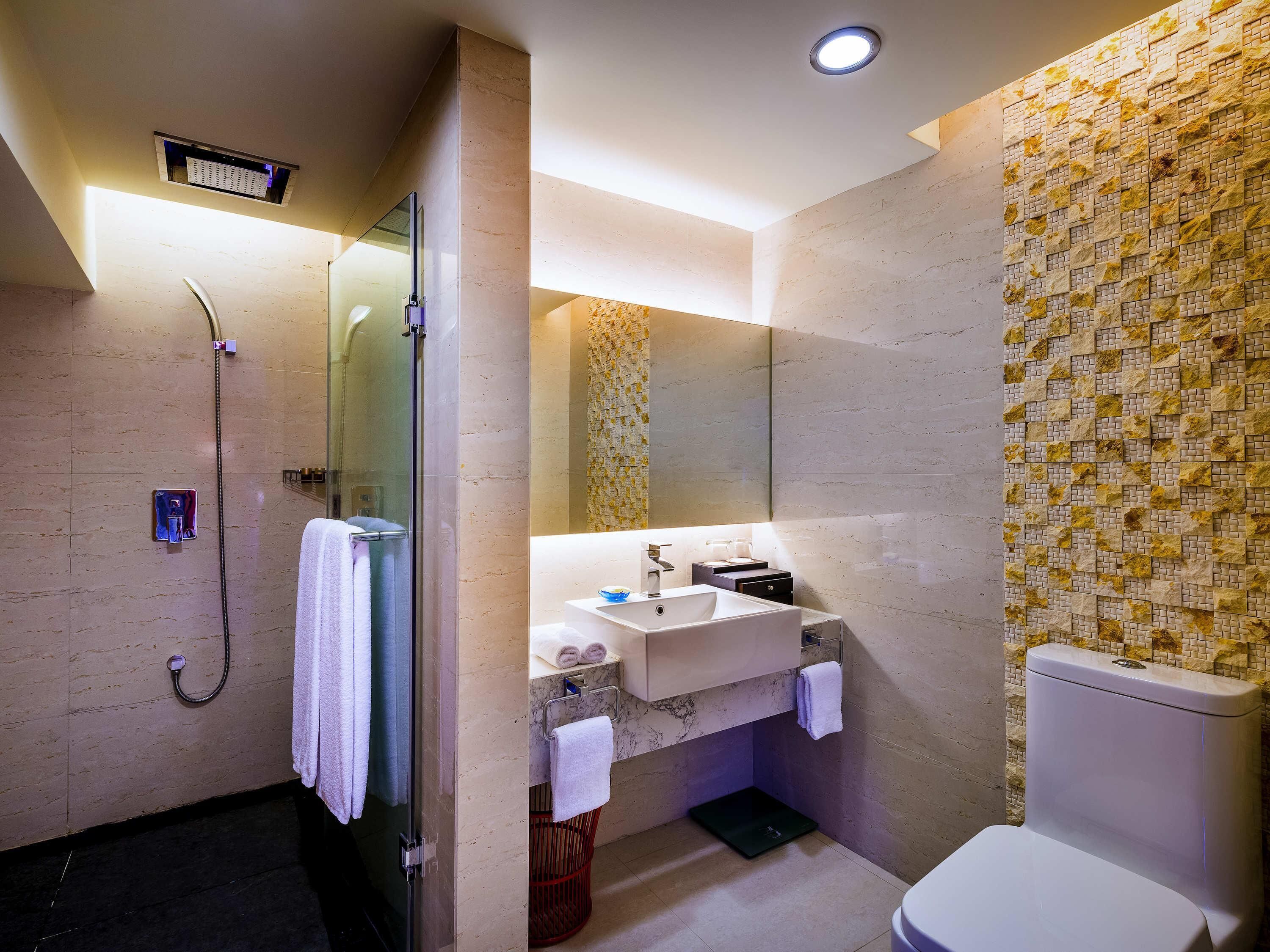 A modern bathroom with a glass-enclosed shower, a marble sink, and a toilet.