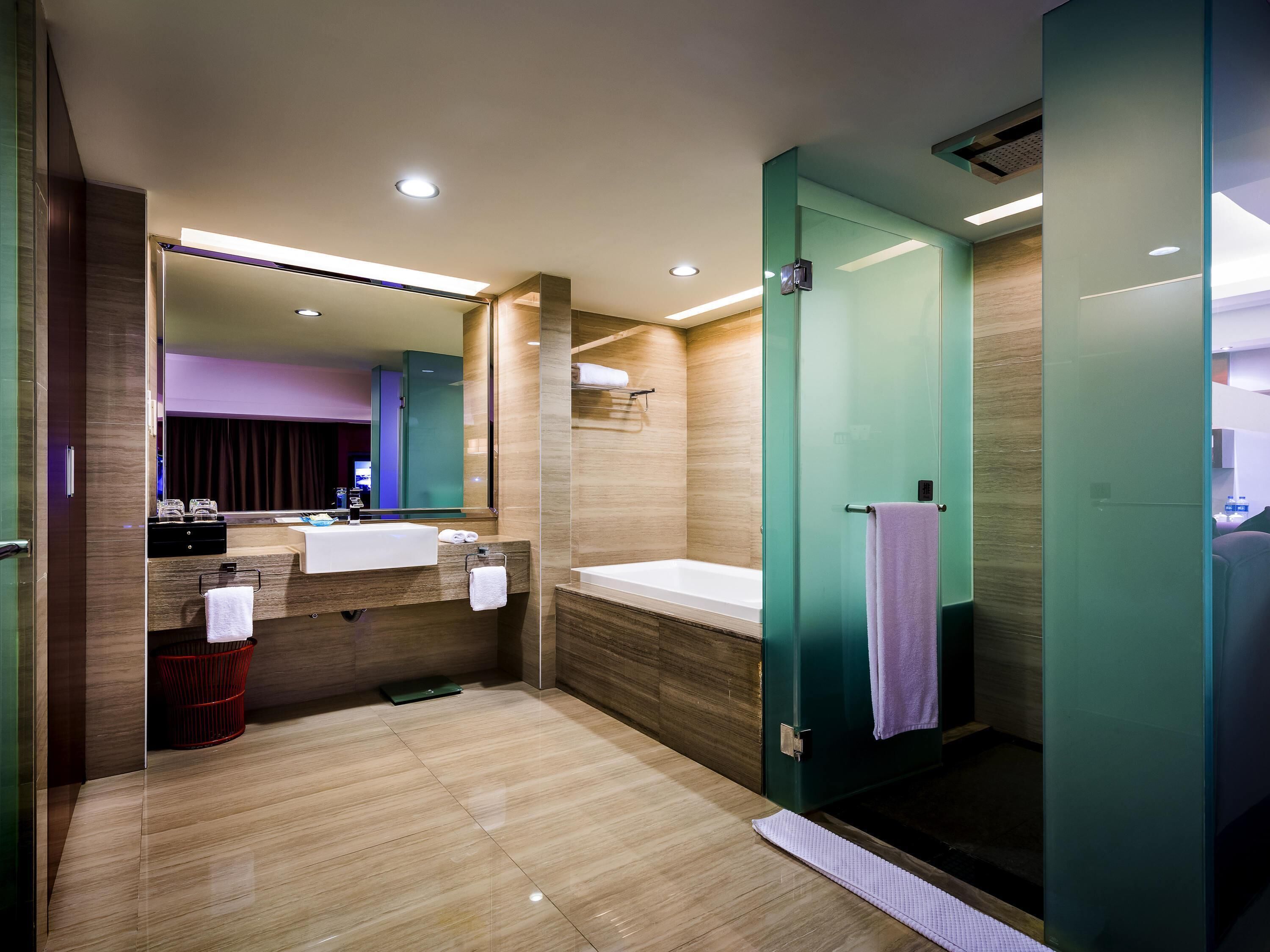 A modern bathroom with a large mirror, a sink, a bathtub, and a shower area.