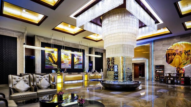 Eine geräumige Lobby mit Empfangstresen, Sitzbereich und einer großen Chandelier.