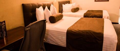 A hotel room with two beds, a desk, and a chair.