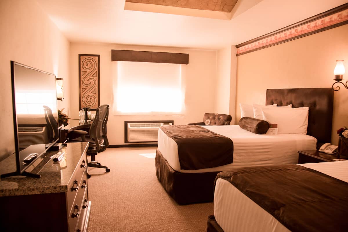 Una habitación de hotel con cama, escritorio, silla, espejo y ventana.