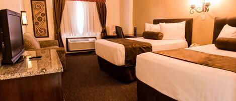 A hotel room with two beds, a desk, a television, and a window with curtains.