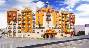 A multi-story hotel with balconies, a central dome, and a parking lot in front. - Hotel Maria Bonita Consulado Americano (Ciudad Juárez)