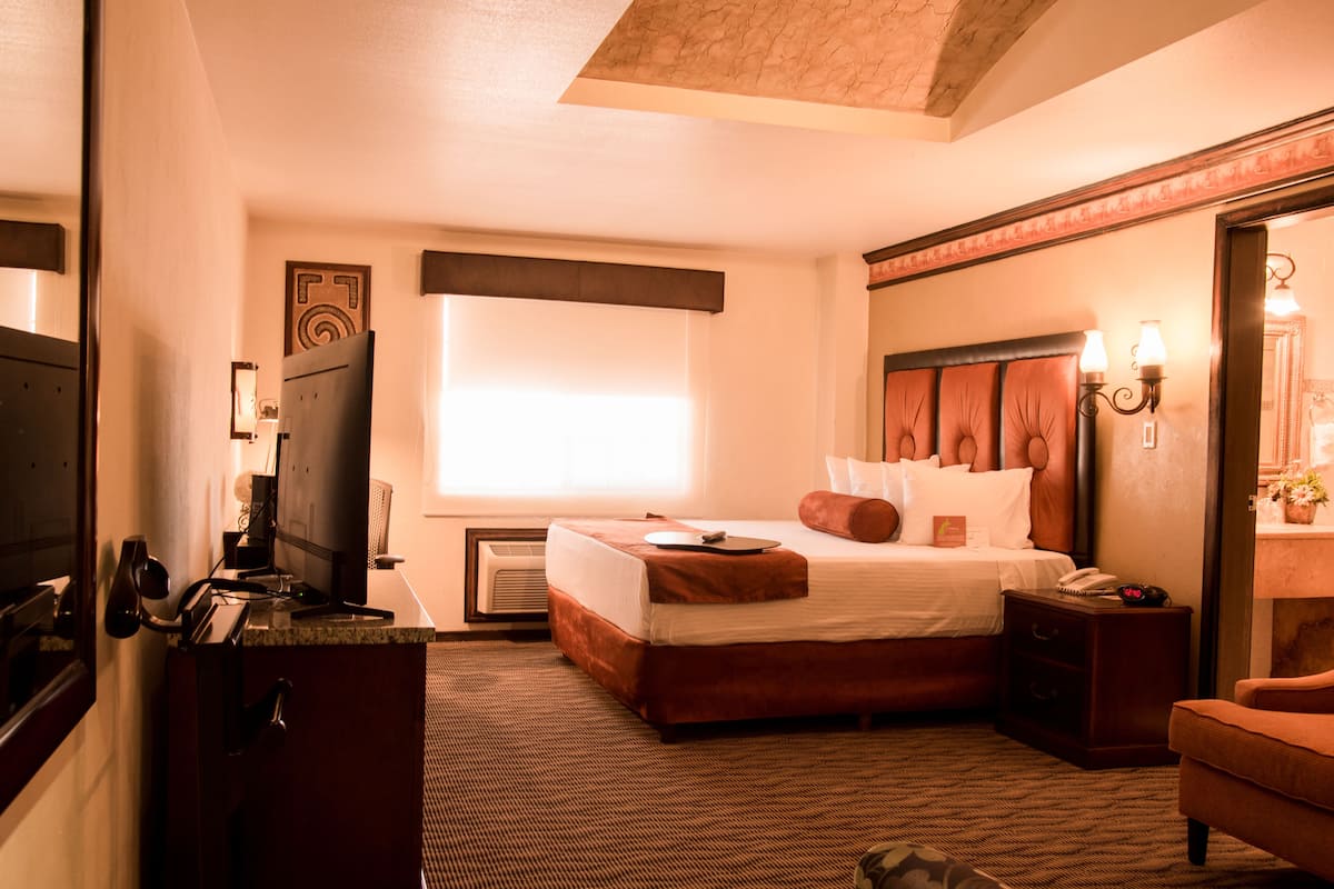 Habitación de hotel con una cama grande, un escritorio con computadora, una silla y una mesita.