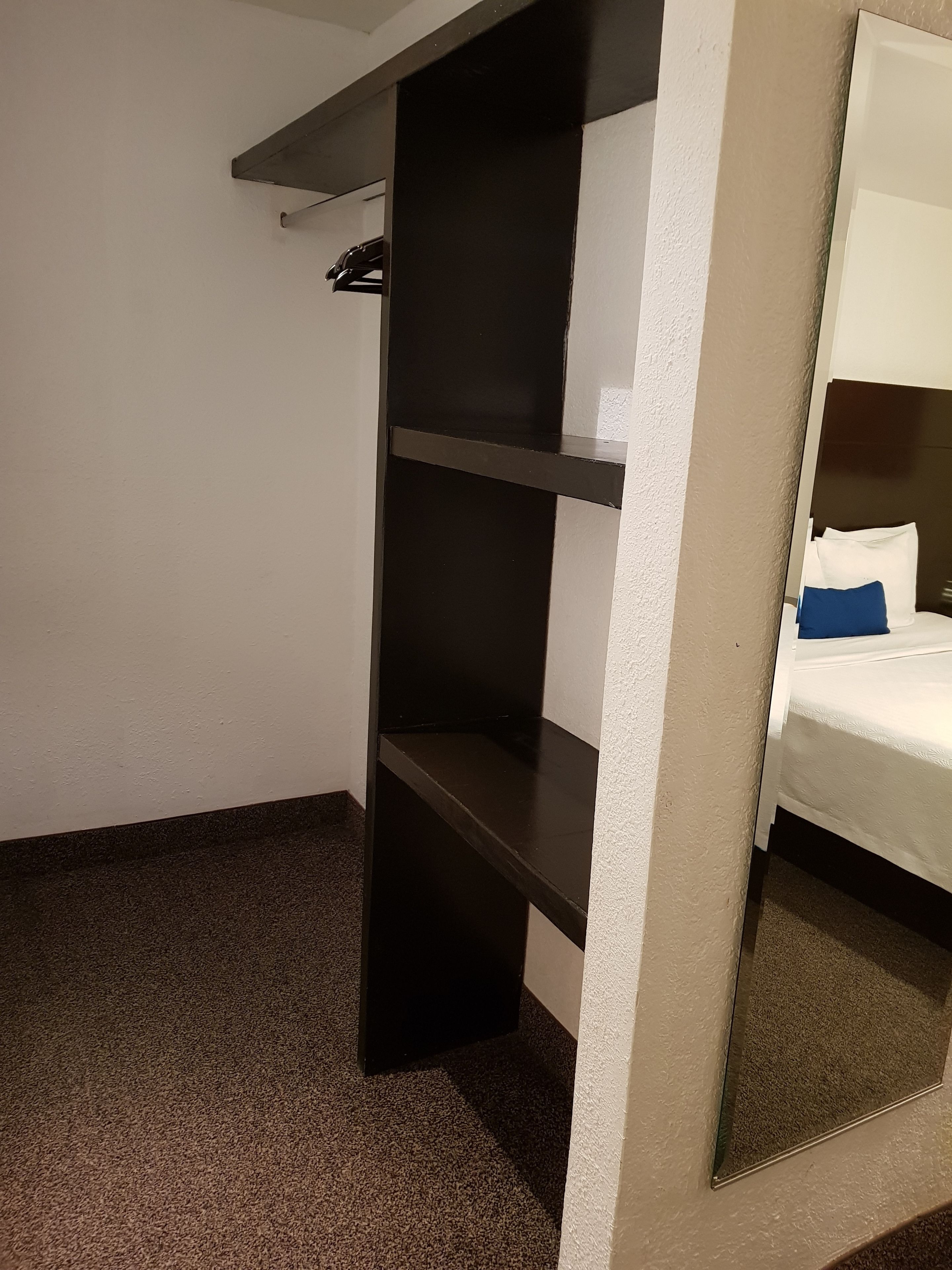 A room with a bunk bed, a small shelf unit, and a mirror.