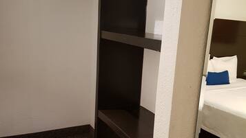 A room with a bunk bed, a small shelf unit, and a mirror.