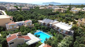 A residential area with modern houses, a swimming pool, and solar panels on rooftops. - Elea apartments (Chania)