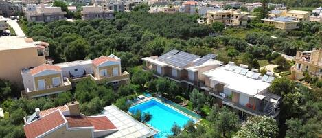 A residential area with modern houses, a swimming pool, and solar panels on rooftops.