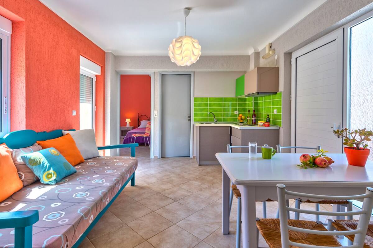 A bright room with a sofa, a dining table, and a kitchen area.