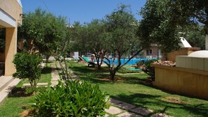 A well-maintained outdoor area with a swimming pool, lounge chairs, and a stone pathway. - Elea apartments (Chania)