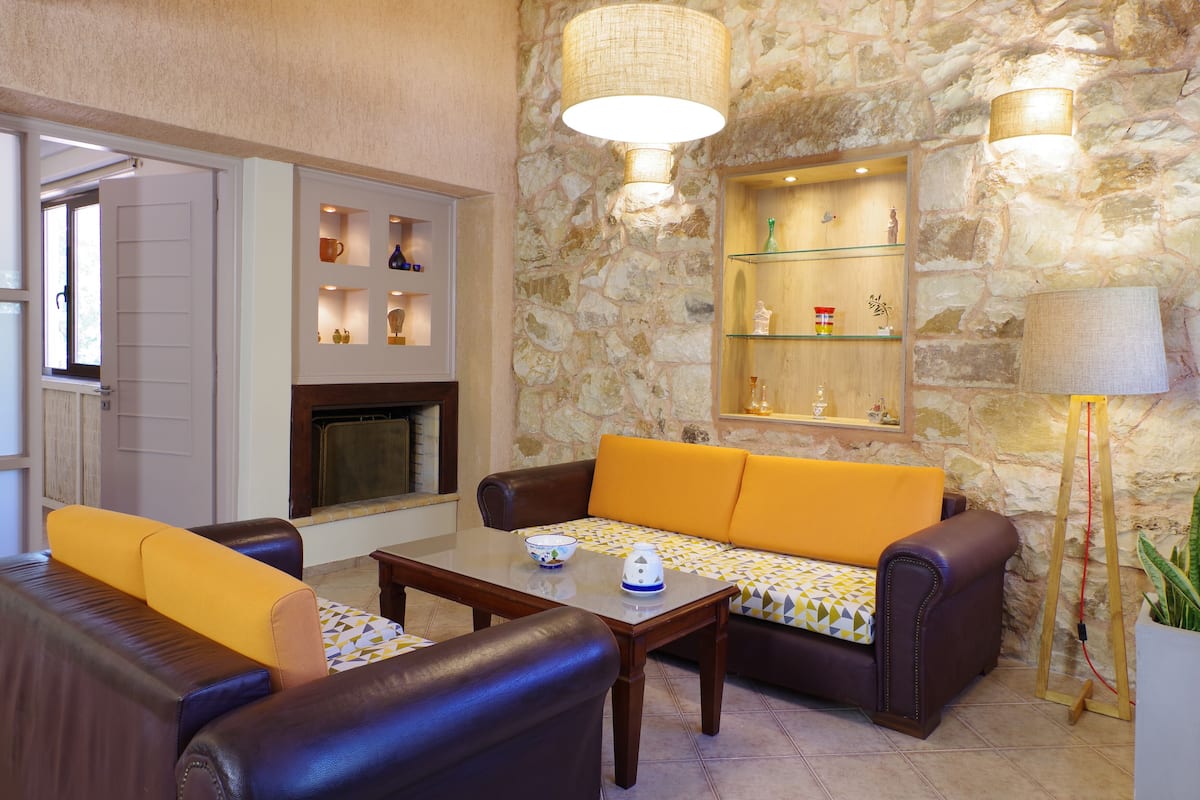 A cozy living room with a stone wall, a fireplace, a sofa, and a coffee table.