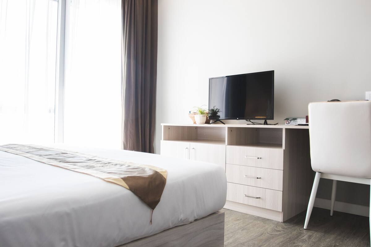 Ein Hotelzimmer mit Bett, Schreibtisch, Fernseher und einem Fenster mit Vorhängen.