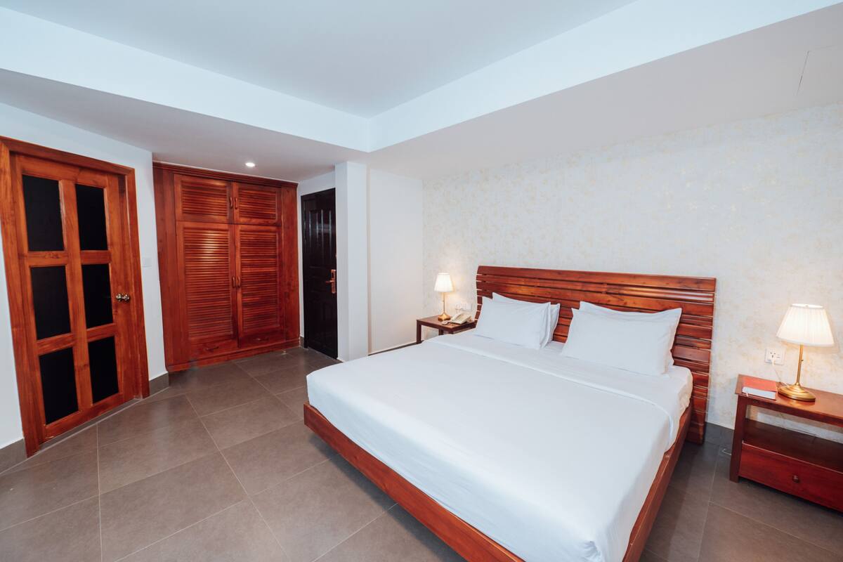 Ein Hotelzimmer mit einem großen Bett, einem Holzschrank und zwei Nachttischen mit Lampen.