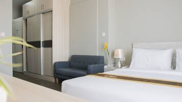 Een hotelkamer met een bed, een bureau, een stoel, een kledingkast en een nachtkastje met een lamp.