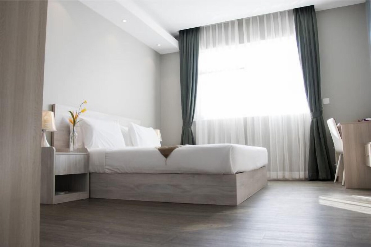 A modern bedroom with a bed, nightstands, and a desk.