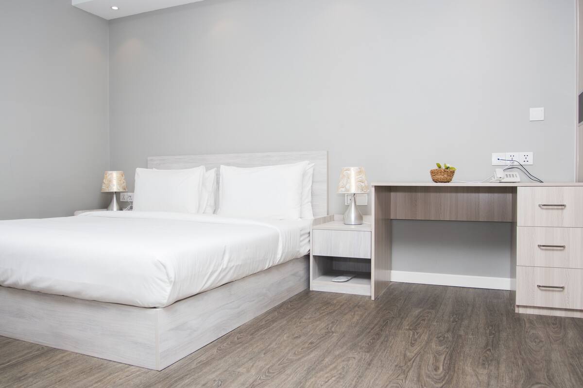 Ein modernes Schlafzimmer mit Bett, Nachttischen, Schreibtisch und Kleiderschrank.