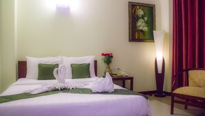 A hotel room with a neatly made bed, a vase with flowers, a lamp, and a chair. - V N E Hotel (Phnom Penh)