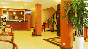 A hotel lobby with a reception desk, seating area, and a staircase. - V N E Hotel (Phnom Penh)