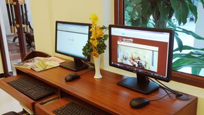 A wooden desk with two monitors, a keyboard, and a mouse. - V N E Hotel (Phnom Penh)