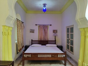 Une chambre à coucher avec un lit, un ventilateur de plafond, une fenêtre et des rideaux.