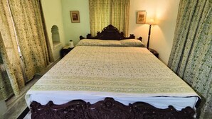 Une chambre avec un grand lit, deux lampes de chevet et des rideaux.