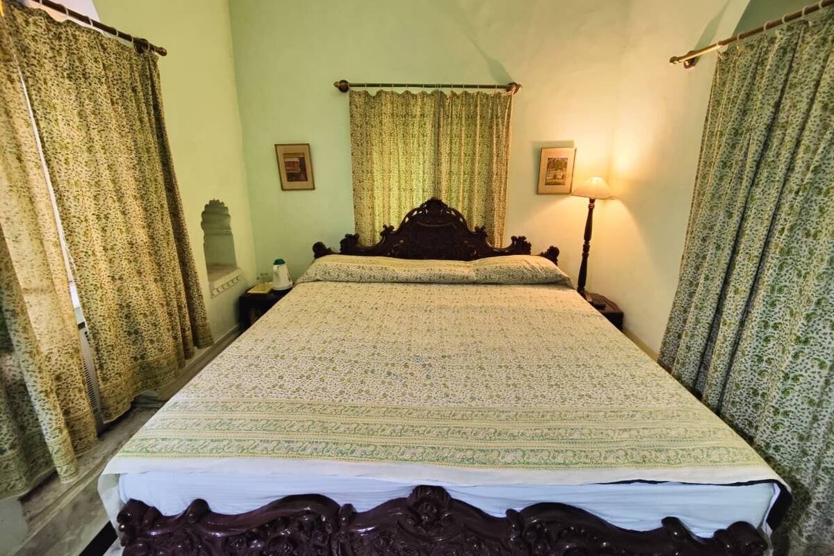 Ein Zimmer mit einem großen Bett, zwei Nachttischlampen und Vorhängen.