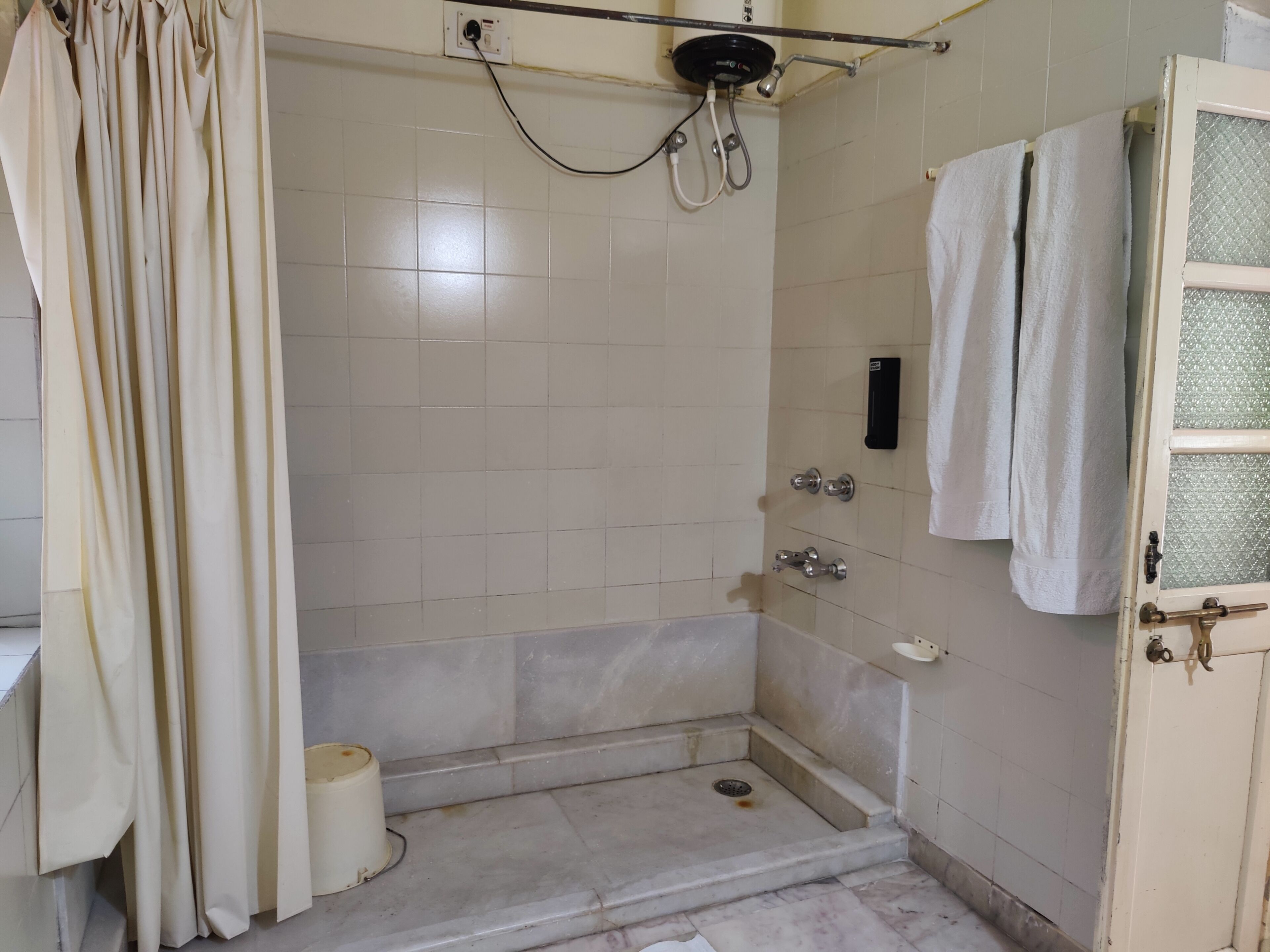 A small, tiled bathroom with a shower, a toilet, and a sink.