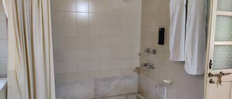 Un baño pequeño con azulejos, que incluye una ducha, un inodoro y un lavamanos.