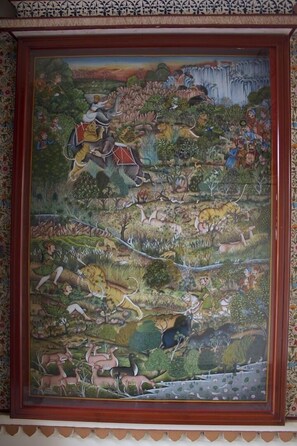 A framed mural depicting a vibrant jungle scene with various animals and people. - Palkiya Haveli - A Heritage Home (Kota)