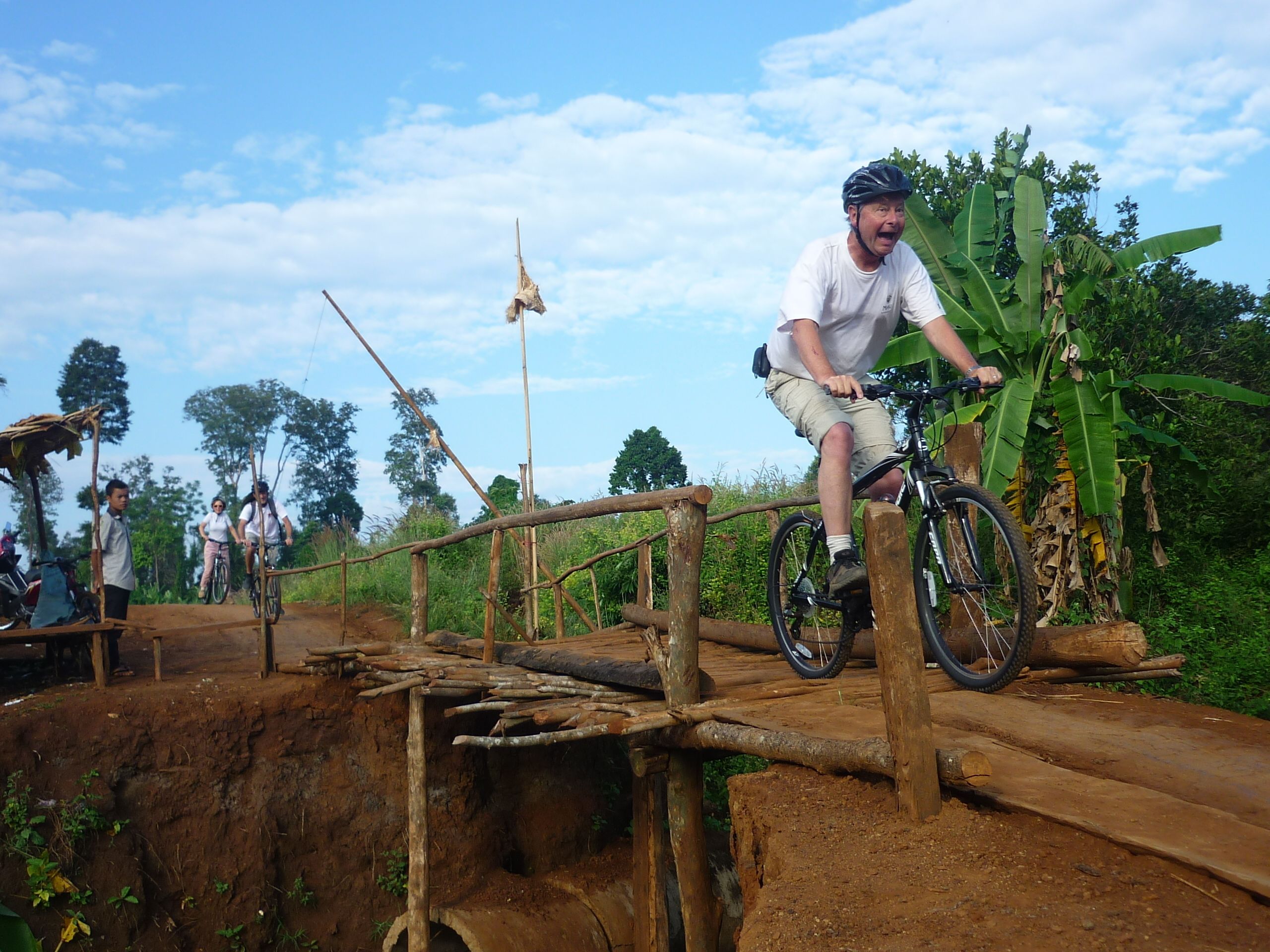 A person riding a bicycle on a wooden bridge in a natural setting.