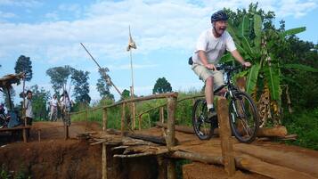 A person riding a bicycle on a wooden bridge in a natural setting.