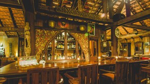 Un bar con mobiliario de madera, un arco decorativo y una variedad de botellas.