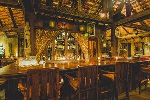 A bar with wooden furniture, a decorative arch, and a variety of bottles.