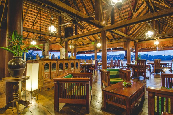 Un restaurante interior con mobiliario de madera, luces colgantes y vistas a las montañas.