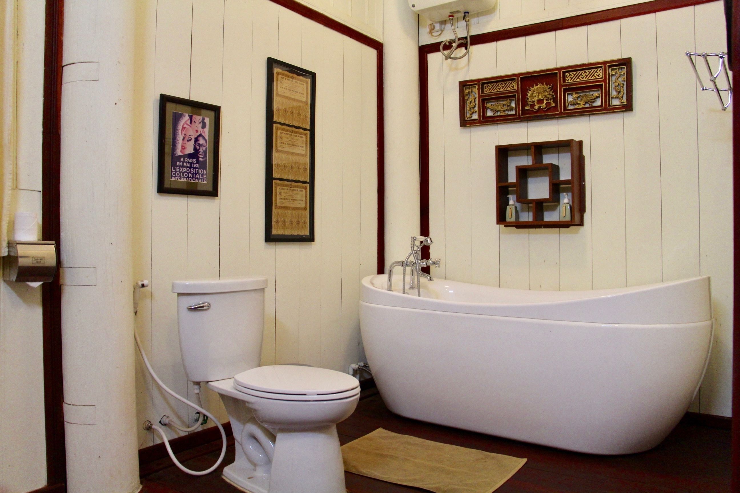 A bathroom with a toilet, a bathtub, and framed documents on the wall.