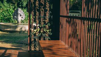 Um jardim com uma fonte, um portão de metal ornamental e um caminho.