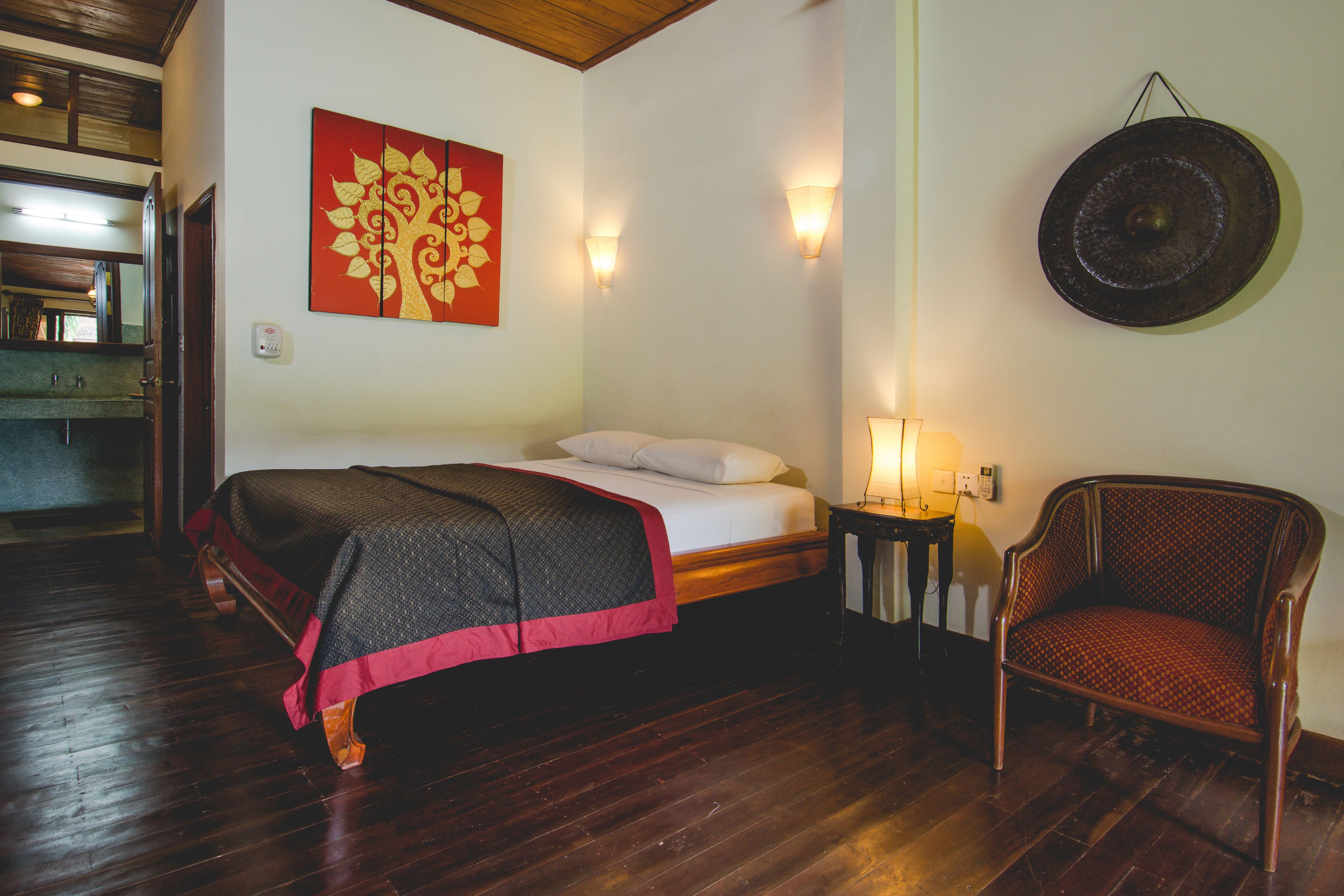 Une pièce comprenant un lit, une chaise, une lampe fixée au mur et un élément décoratif mural.