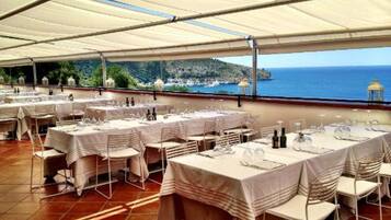 An outdoor dining area with tables set for a meal, overlooking a coastal landscape.