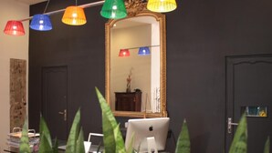 A room with a desk, an Apple iMac, a mirror, and colorful hanging lamps. - b11 Hôtel (Nice)