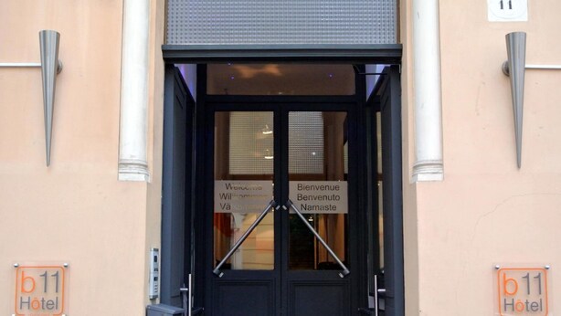 A hotel entrance with a sign reading "Bienvenue" and "Welcome" in multiple languages, a number "11" above the door, and a "b 11 Hotel" sign on the wall. - b11 Hôtel (Nice)