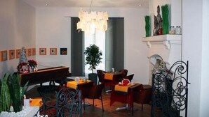 A modern dining area with a piano, dining tables, chairs, and a chandelier. - b11 Hôtel (Nice)