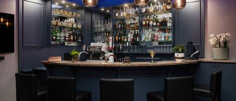 A bar area with a counter, bar stools, and shelves stocked with liquor bottles.