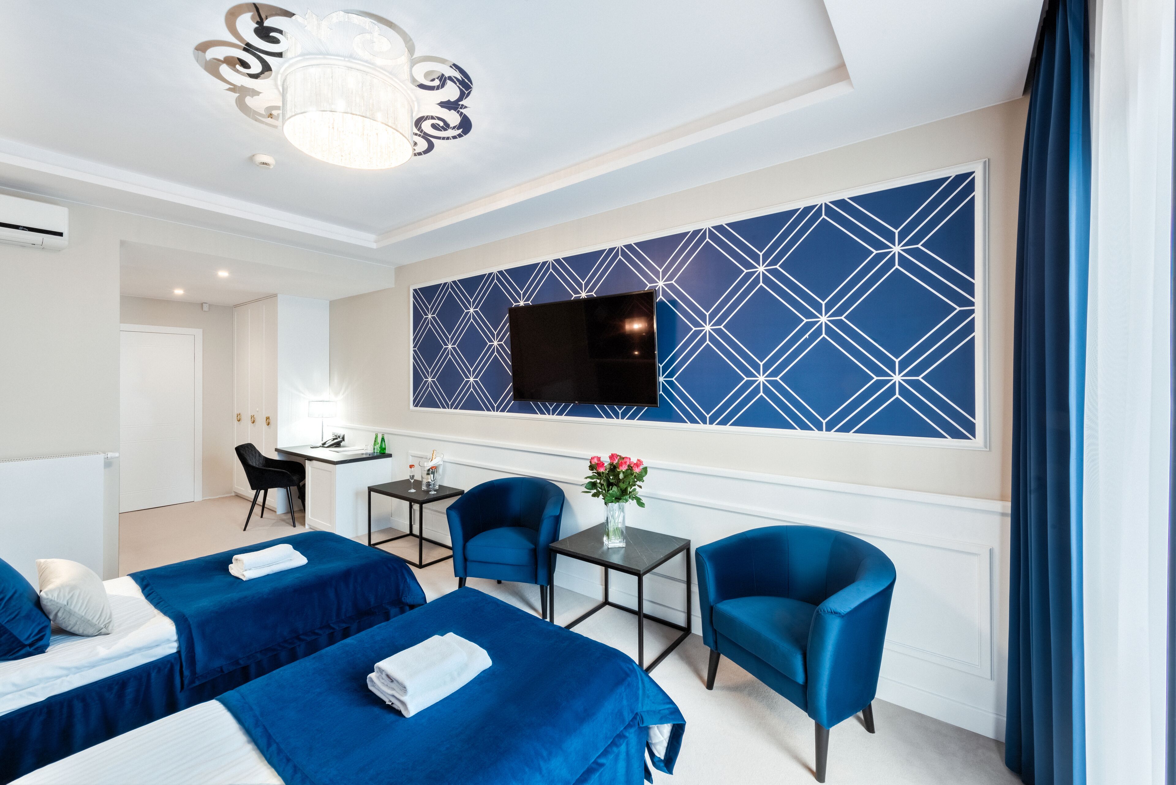 Habitación de hotel con dos camas, un escritorio, una silla, un televisor y un adorno en la pared.