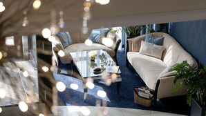 A modern lounge area with a sofa, armchair, and coffee table, featuring a basket and a vase with flowers. - Villa Hoff Wellness & SPA Hotel (Rewal)