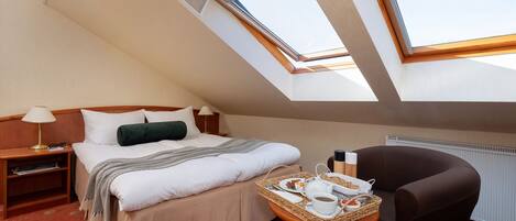 Quarto de hotel com cama, uma cadeira, mesa pequena com itens de café da manhã e um domínio.